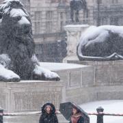 People walk through the snow in Trafalgar Square, central London